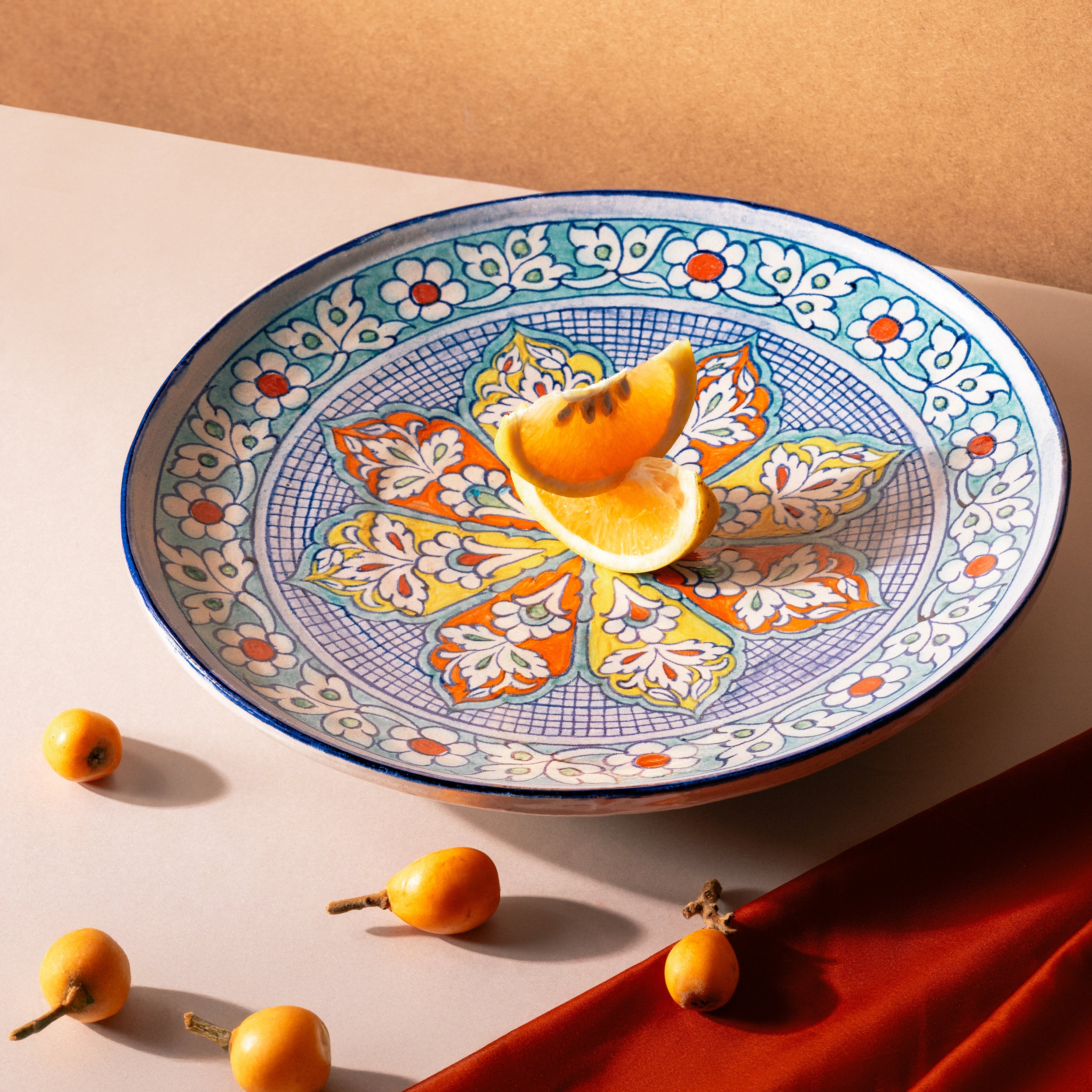 Decorative plate with floral patterns on a beige surface with fruits.
